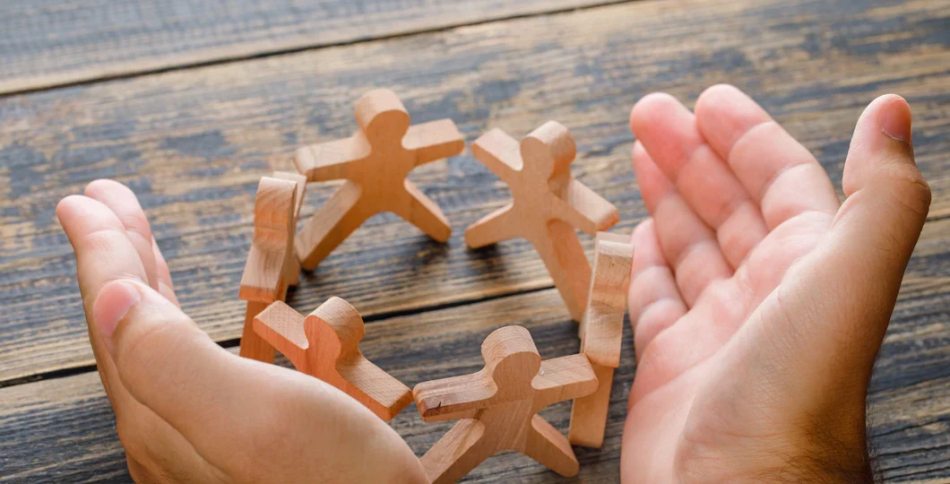 business-success-concept-wooden-table-top-view-hands-protecting-wooden-figures-people_176474-9273